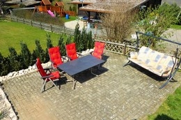 Die Sonnenterrasse mit großem Gartentisch und bequemen Stühlen.